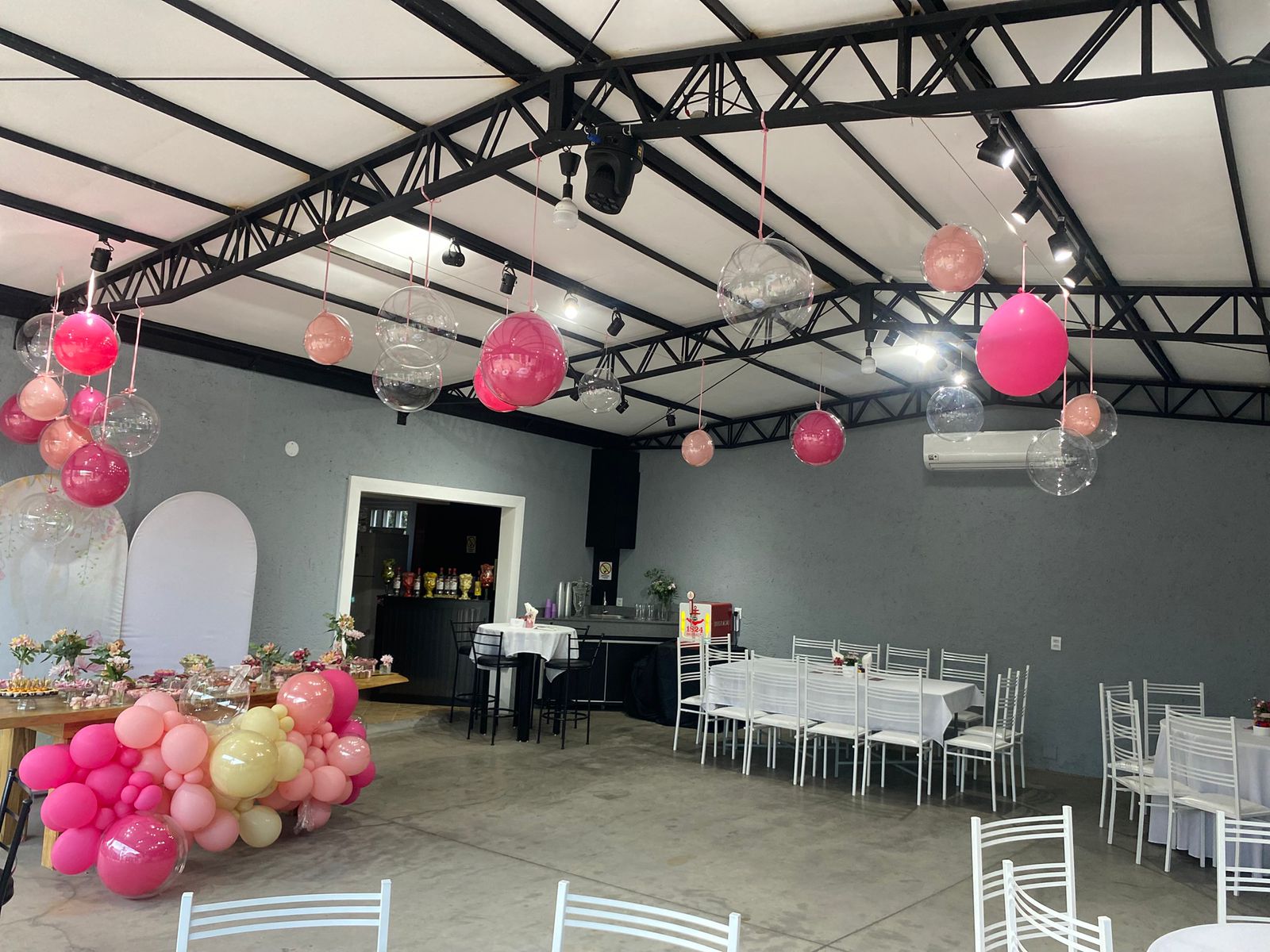 Salão decorado com balões suspensos e mesas postas